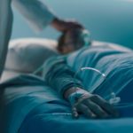 Hospitalized patient lying in a hospital bed at night, a doctor is taking care of her, hand close up